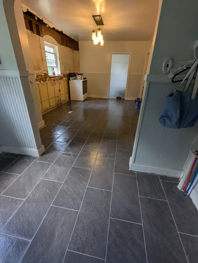 Charcoal stone-look floor tile laid in an offset pattern through an older home